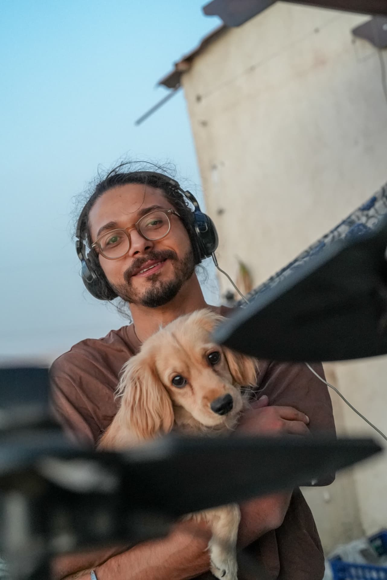 Asaad wearing headphones, holding his dog Gambry outdoors at dusk